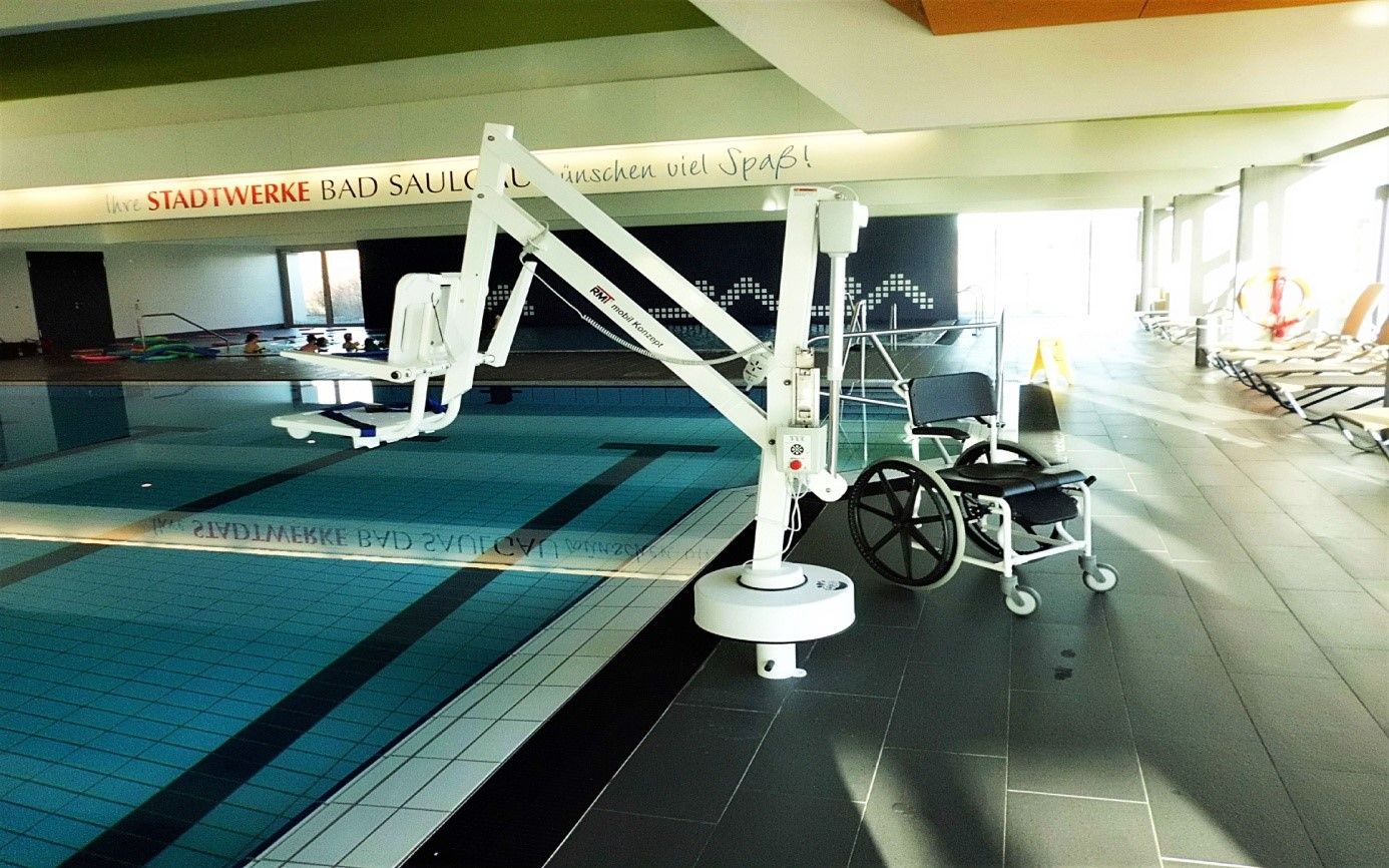 Hydraulik-Lift, dahinter flache Treppen mit beidseitigen Haltegriffen als Einstiegshilfen ins Schwimmbecken